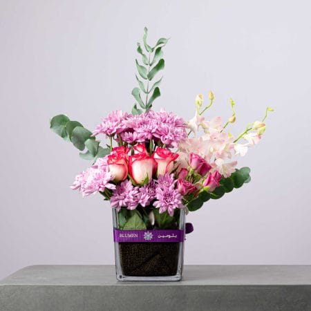 Delicate pink and lilac floral arrangement with orchids and roses in a BLUMEN vase.
