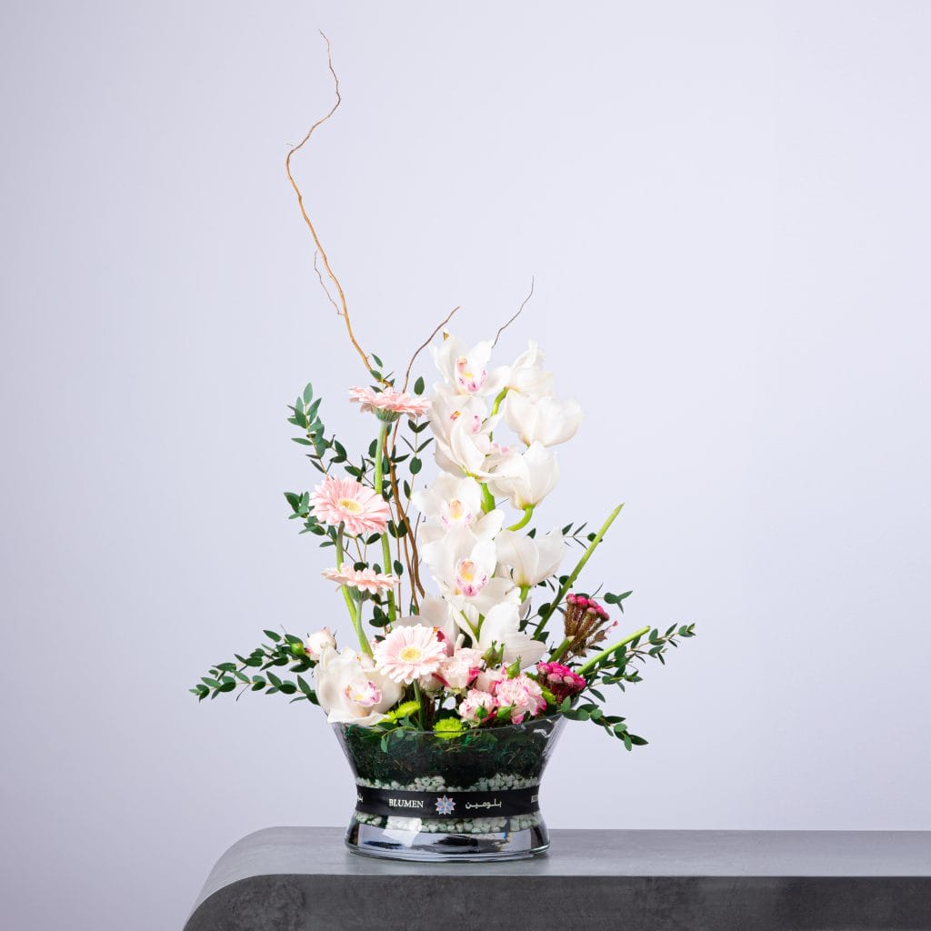 Elegant white and pink arrangement with orchids, gerberas, and soft blooms in a BLUMEN bowl vase.