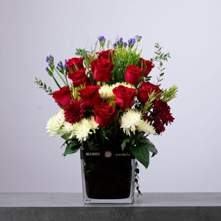 Floral arrangement with red roses and white chrysanthemums in a glass vase.