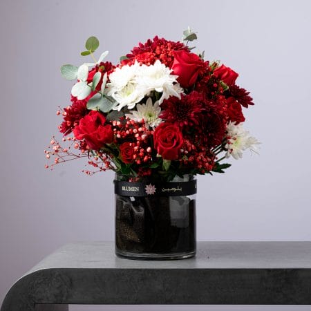 Luxury red and white flower arrangement with roses, chrysanthemums, and eucalyptus in a black BLUMEN vase.