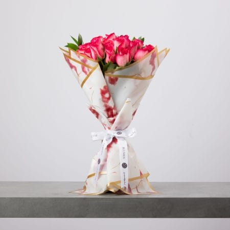 Pink rose bouquet wrapped in marbled white and gold paper.