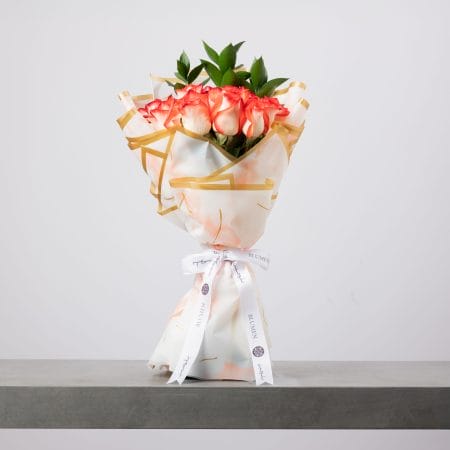 Peach rose bouquet wrapped in marbled white and gold paper.