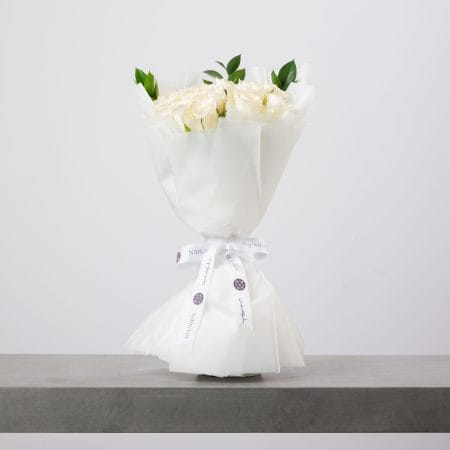 باقة ورود بيضاء أنيقة ملفوفة بورق أبيض فاخر من بلومن