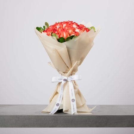 باقة ورود برتقالية فاخرة ملفوفة بورق عاجي من بلومن