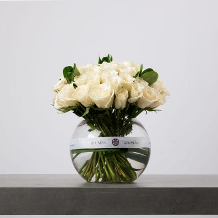 White rose bouquet arranged in a clear round glass vase