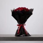 Red rose bouquet wrapped in black paper with red ribbon