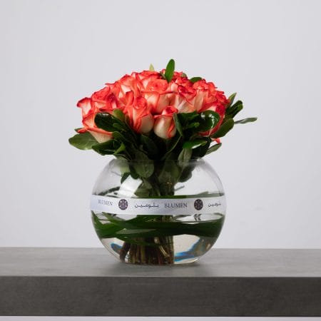 Orange rose bouquet arranged in a clear round glass vase