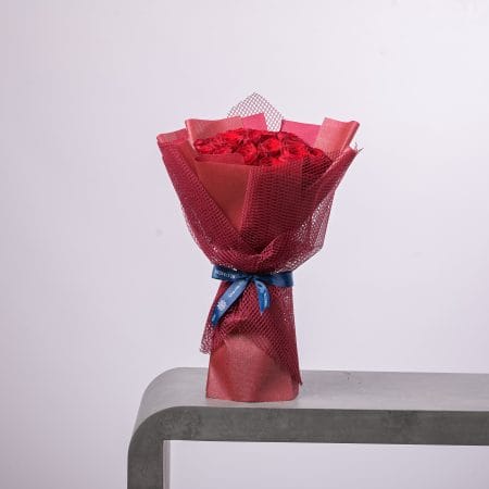 Red rose bouquet wrapped in red mesh with a blue ribbon.