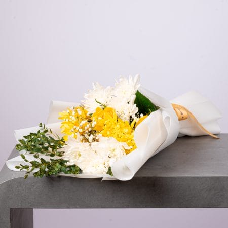 باقة زهور صفراء وبيضاء أنيقة ملفوفة بورق أبيض من بلومن