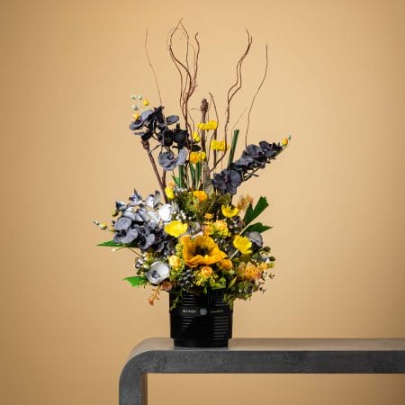 Artificial floral arrangement with yellow and gray blooms in a black ribbed pot.