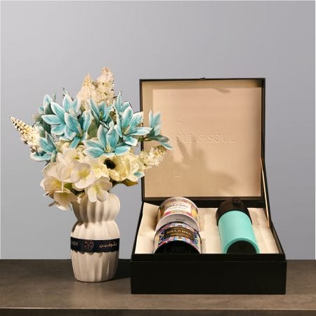 Elegant floral arrangement with soft blue and ivory flowers in a sculpted ceramic vase.