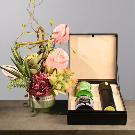 Elegant floral arrangement with pink anthuriums and greenery arranged in a green vase with flowing stems.