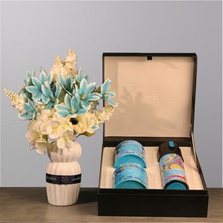 Elegant floral arrangement with soft blue and ivory flowers in a sculpted ceramic vase.
