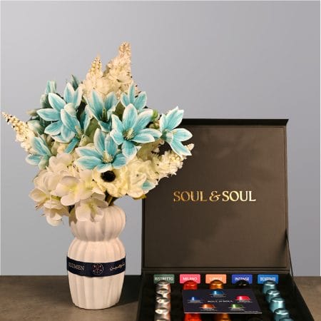 Elegant floral arrangement with soft blue and ivory flowers in a sculpted ceramic vase.