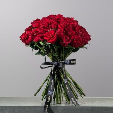 The Devoted Whisper bouquet featuring elegant red roses arranged in a romantic floral design