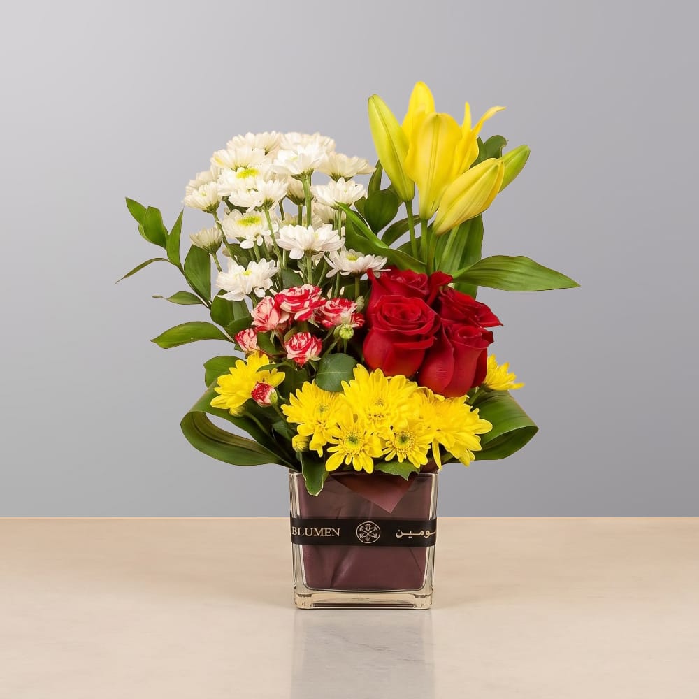 A cheerful floral arrangement featuring premium blooms, delicate seasonal flowers, and lush greenery, elegantly arranged in a decorative vase.