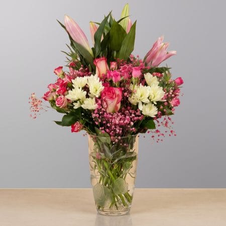 A graceful floral arrangement featuring premium blooms, delicate seasonal flowers, and fresh greenery, elegantly arranged in a decorative vase.