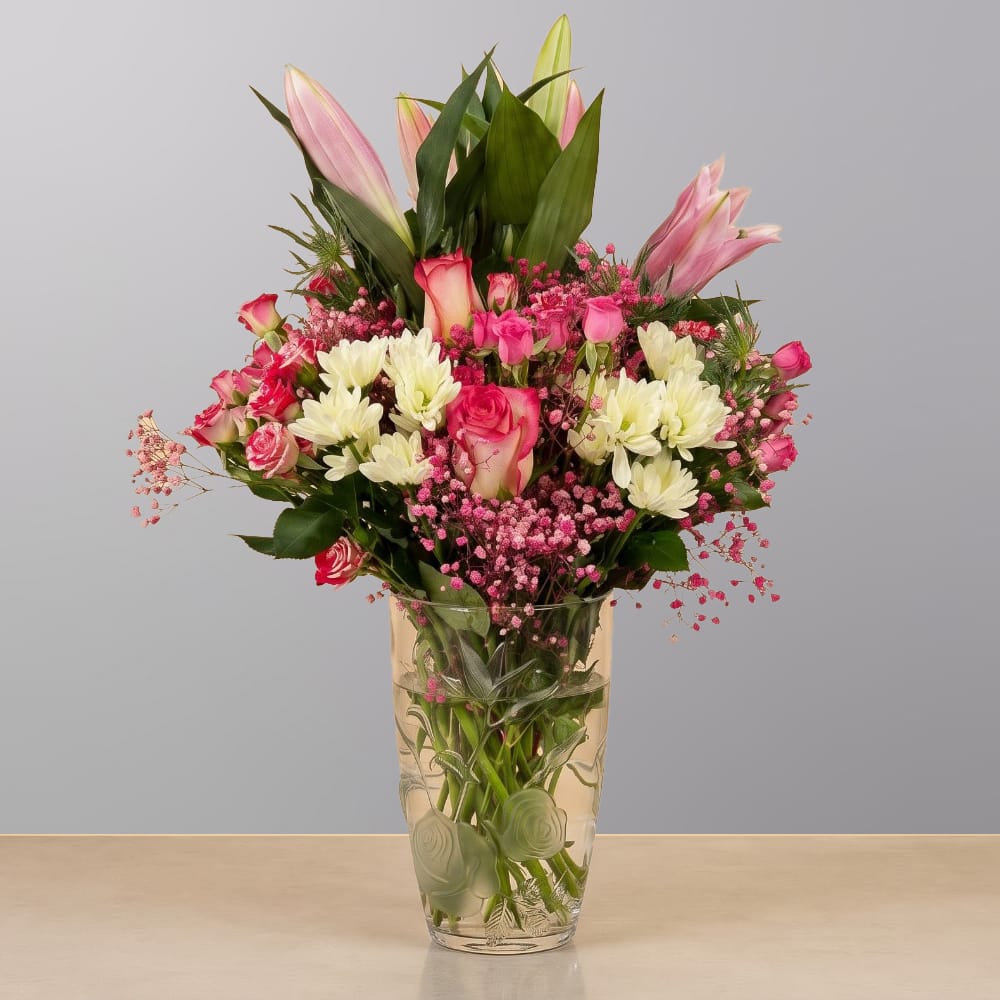 A graceful floral arrangement featuring premium blooms, delicate seasonal flowers, and fresh greenery, elegantly arranged in a decorative vase.