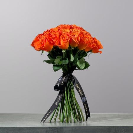 A hand-tied bouquet of vibrant orange roses, elegantly finished with a signature ribbon.