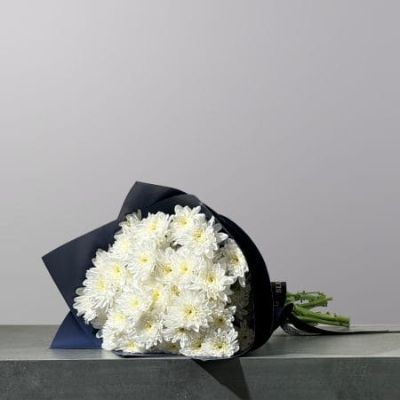 A hand-tied bouquet of pristine white chrysanthemums, elegantly wrapped in premium floral paper and finished with a signature ribbon.