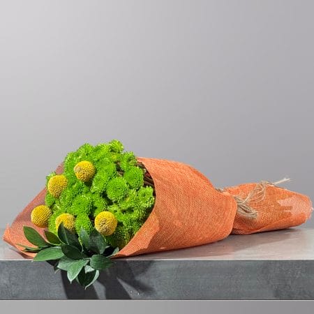 A hand-tied bouquet featuring vibrant green chrysanthemums, golden billy buttons, fresh foliage, and rustic wrapping, finished with natural twine.