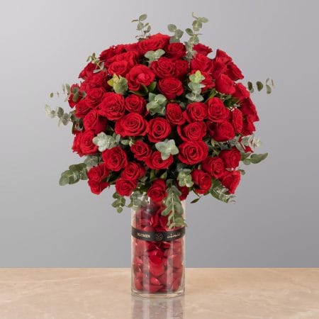 A luxurious floral arrangement featuring premium red roses, white lilies, and seasonal blooms elegantly arranged in a modern decorative vase.