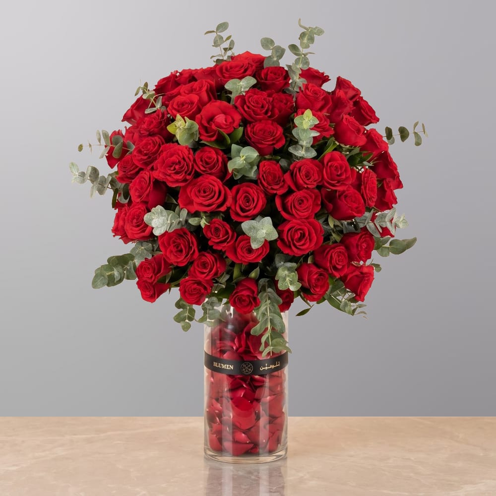 A luxurious floral arrangement featuring premium red roses, white lilies, and seasonal blooms elegantly arranged in a modern decorative vase.