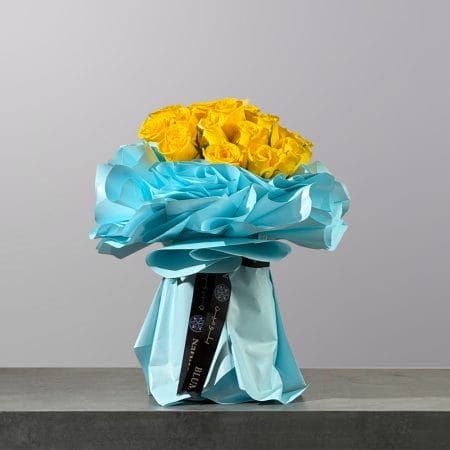 Bouquet of vibrant yellow roses wrapped in elegant sky-blue paper.