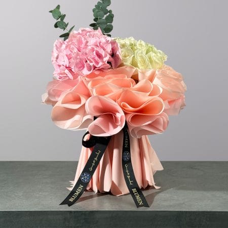 Elegant bouquet featuring pink hydrangea, ivory roses, and eucalyptus wrapped in luxurious blush pink paper.