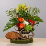 A charming floral arrangement featuring premium roses, seasonal flowers, natural greenery, and rustic accents, beautifully arranged in an elegant decorative container.