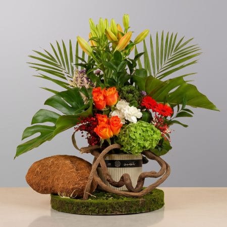 A charming floral arrangement featuring premium roses, seasonal flowers, natural greenery, and rustic accents, beautifully arranged in an elegant decorative container.