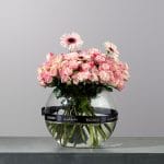 Elegant glass vase arrangement featuring blush pink spray roses, soft pink gerbera daisies, and delicate blooms.