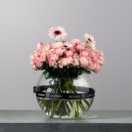 Elegant glass vase arrangement featuring blush pink spray roses, soft pink gerbera daisies, and delicate blooms.