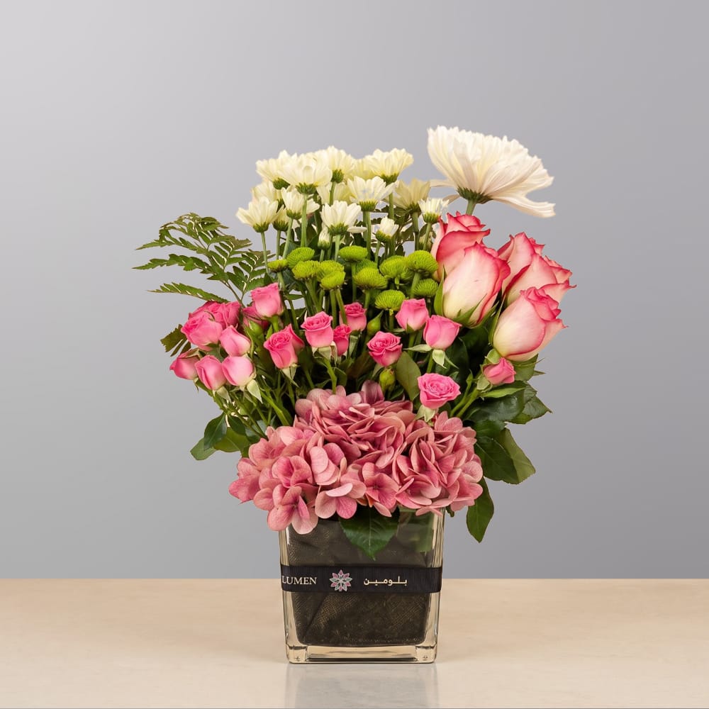 A refined floral arrangement featuring premium blooms, delicate seasonal flowers, and fresh greenery, elegantly arranged in a decorative vase.