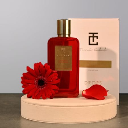 A perfume bottle by Drops with a flower next to it.