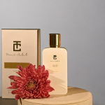 A perfume bottle by Drops with a flower next to it.