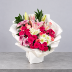 The Lily Muse luxury bouquet featuring pink lilies, vibrant fuchsia roses, blush pink roses, white chrysanthemums and soft lavender blooms, elegantly wrapped in ivory paper by Blumen.