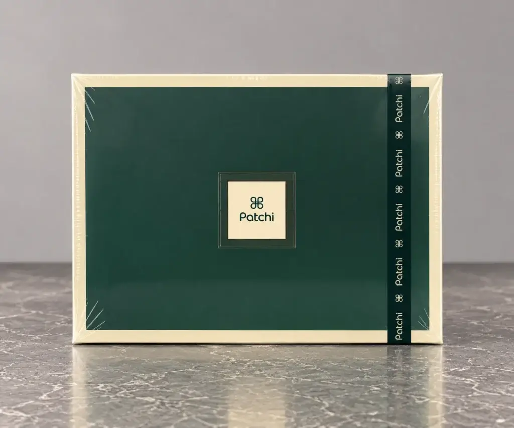 A rectangular dark green box with a ribbon that has the logo of Patchi