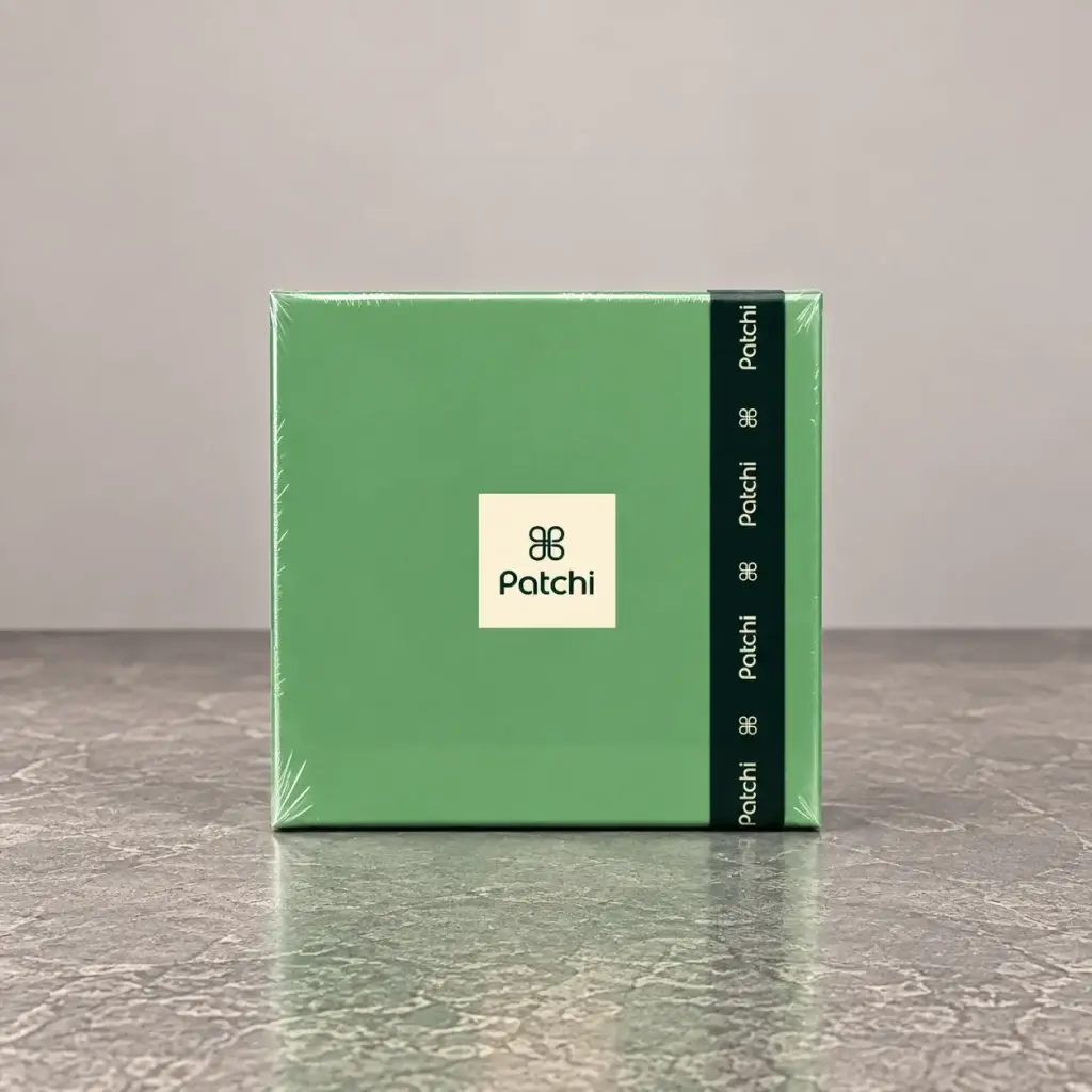 A green box of chocolates with a dark green ribbon made by Patchi.